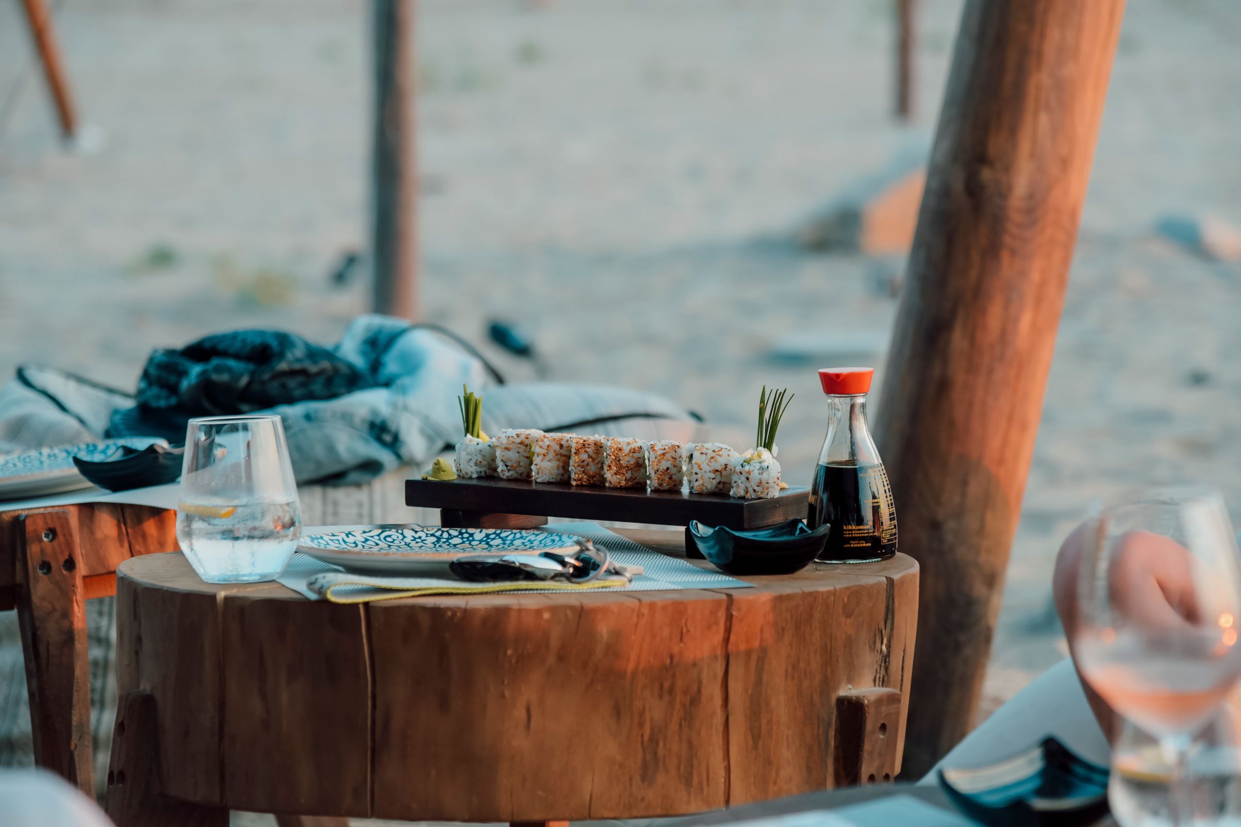 Cozy outdoor setting with sushi and drinks on a rustic wooden table. Perfect for casual dining.