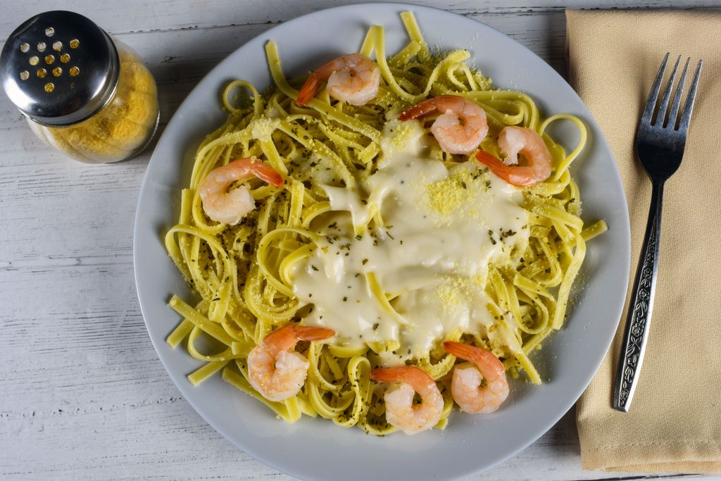 Delicious creamy fettuccine pasta with shrimp, beautifully plated on a rustic wooden table for a gourmet experience.
