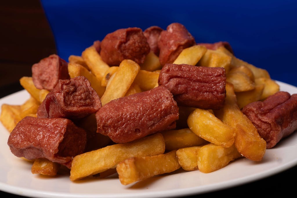 Delicious crispy fries paired with savory red sausages served on a white plate.
