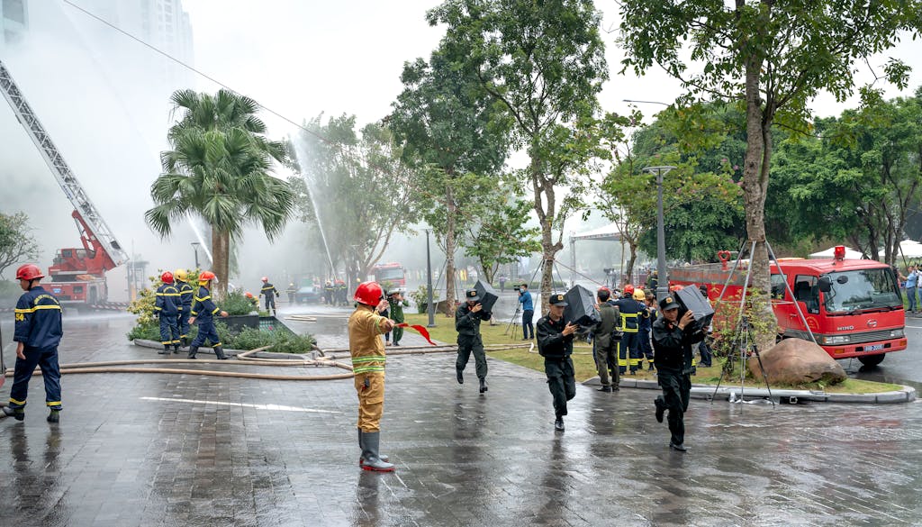 Firefighters and rescuers in action controlling a fire outdoors, using hoses.