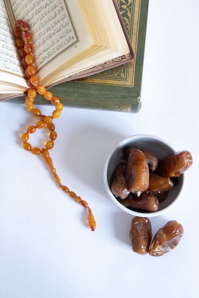 Flat lay of Islamic book, prayer beads, and dates, symbolizing Ramadan spirituality.