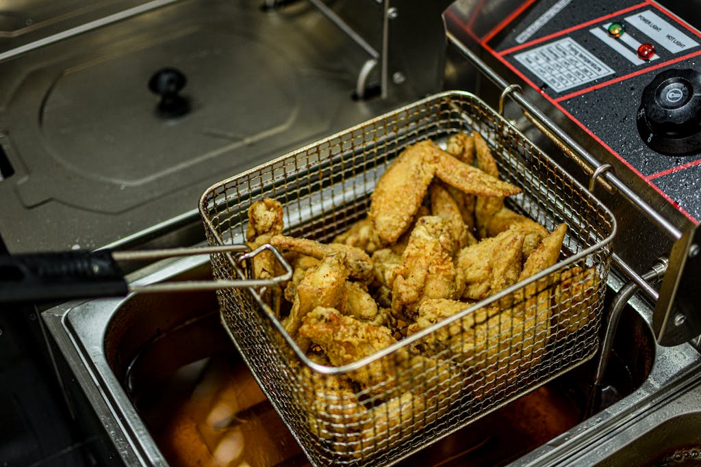 Golden brown chicken wings freshly fried in a commercial deep fryer.