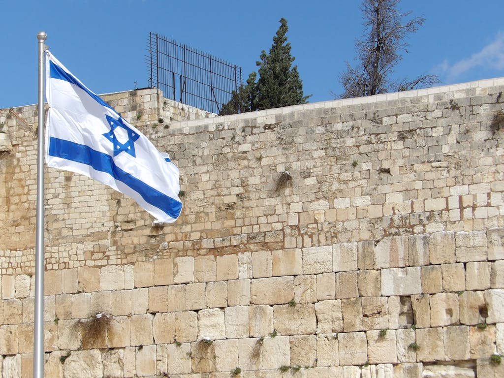 Israeli flag waving at the historic Western Wall, a significant religious site in Jerusalem.