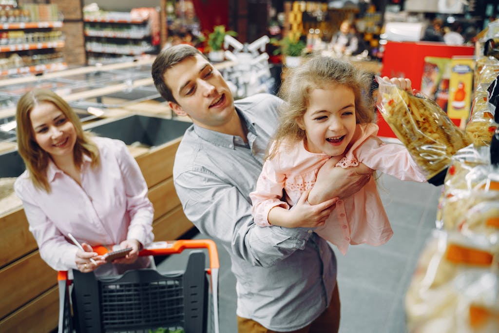 Joyful family of three enjoying grocery shopping together in a supermarket.