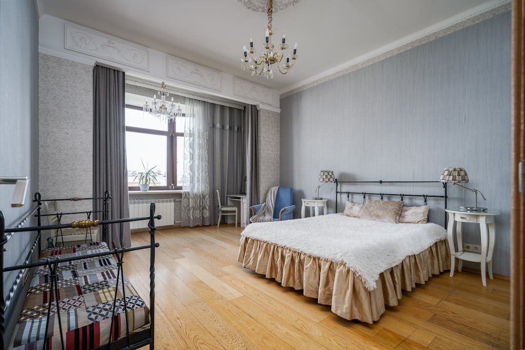 Luxurious bedroom featuring a grand chandelier, elegant furnishings, and classic interior design elements.