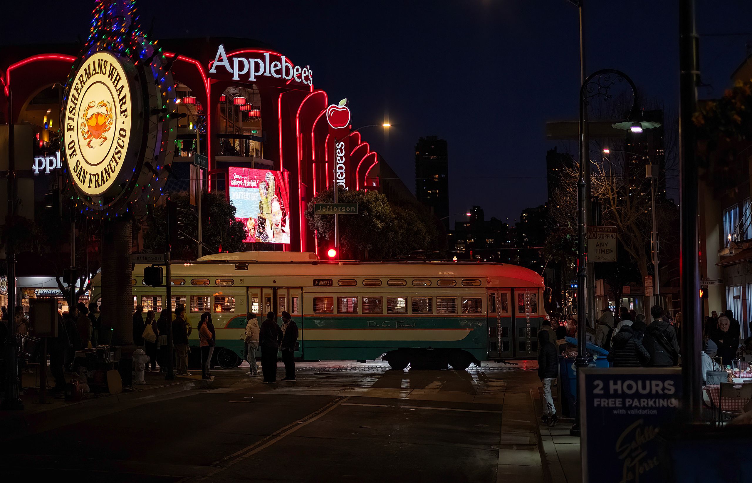 Night scene at Fisherman's Wharf with a tram and neon lights in San Francisco.