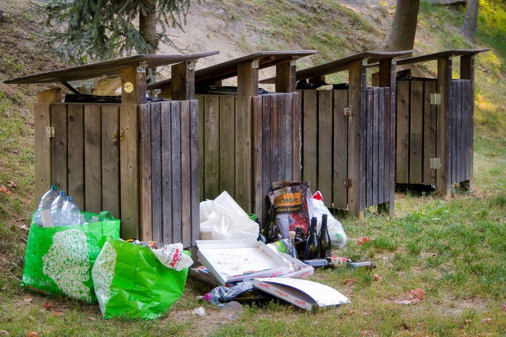 Overflowing garbage bins in a park in Meran highlight littering issues.