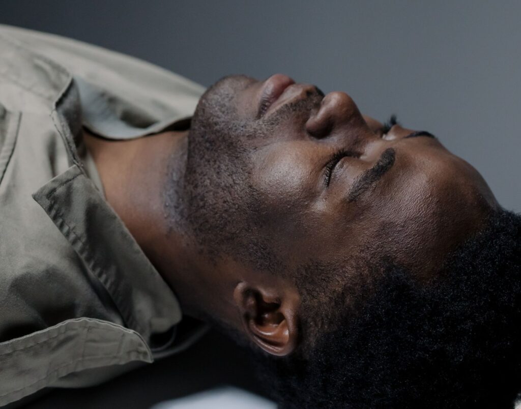Peaceful portrait of a black man lying down with eyes closed in a studio setting.