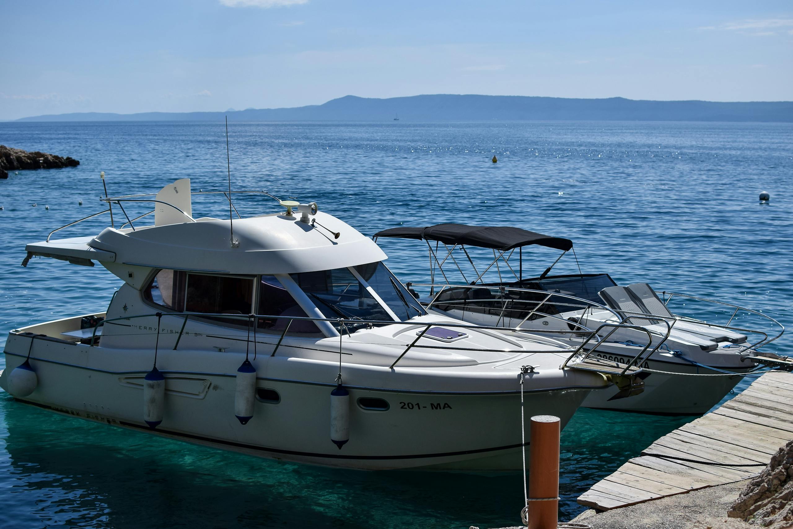 Peaceful scene of motorboats docked by the sea under a clear blue sky, ideal for travel and vacation themes.