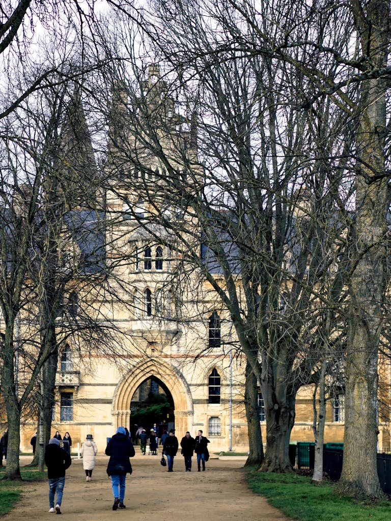 People walk towards the historic Christ Church College in Oxford, England, during a cool day.