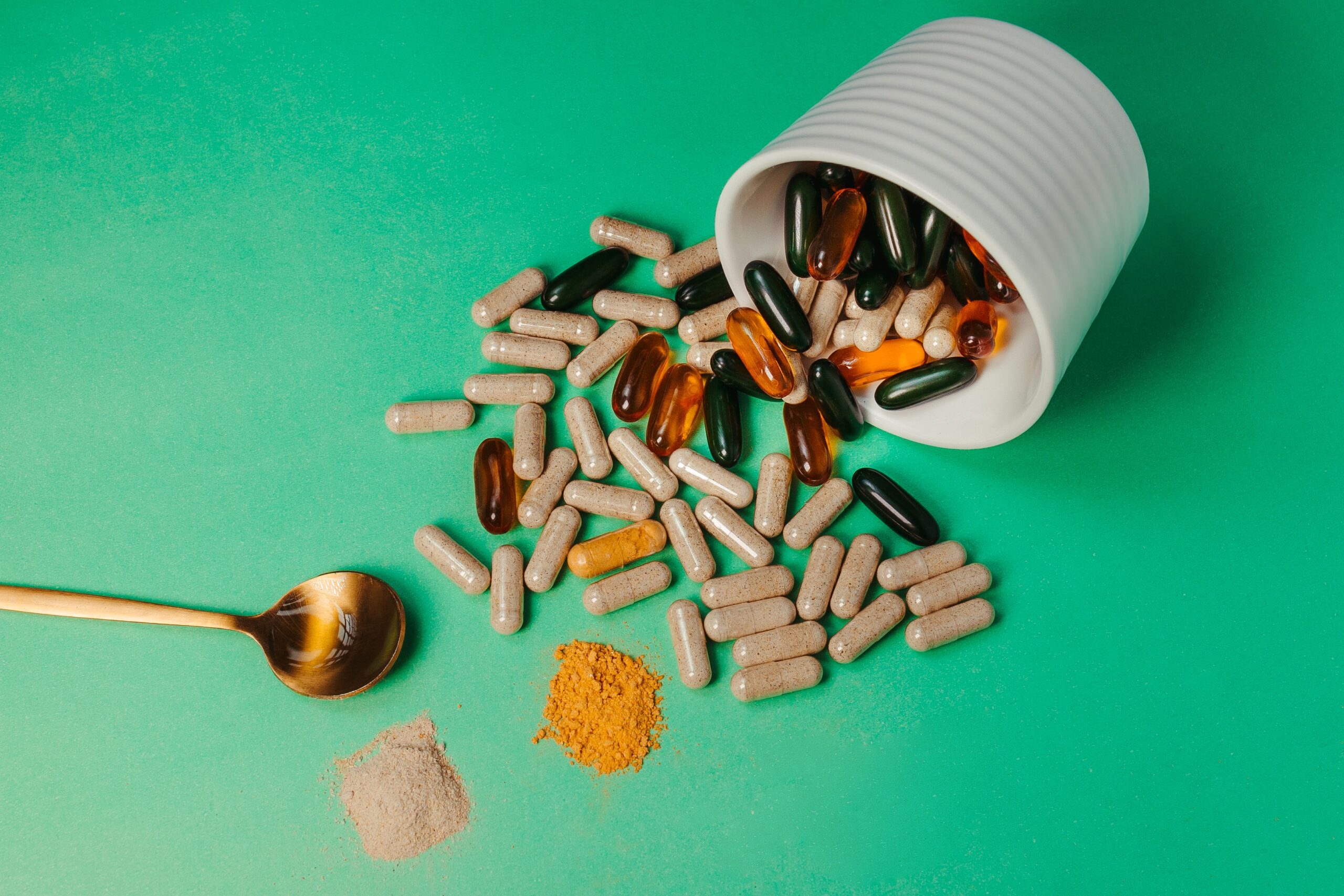 multi-colored-capsules-bowl-and-spoon-on-green-surface
