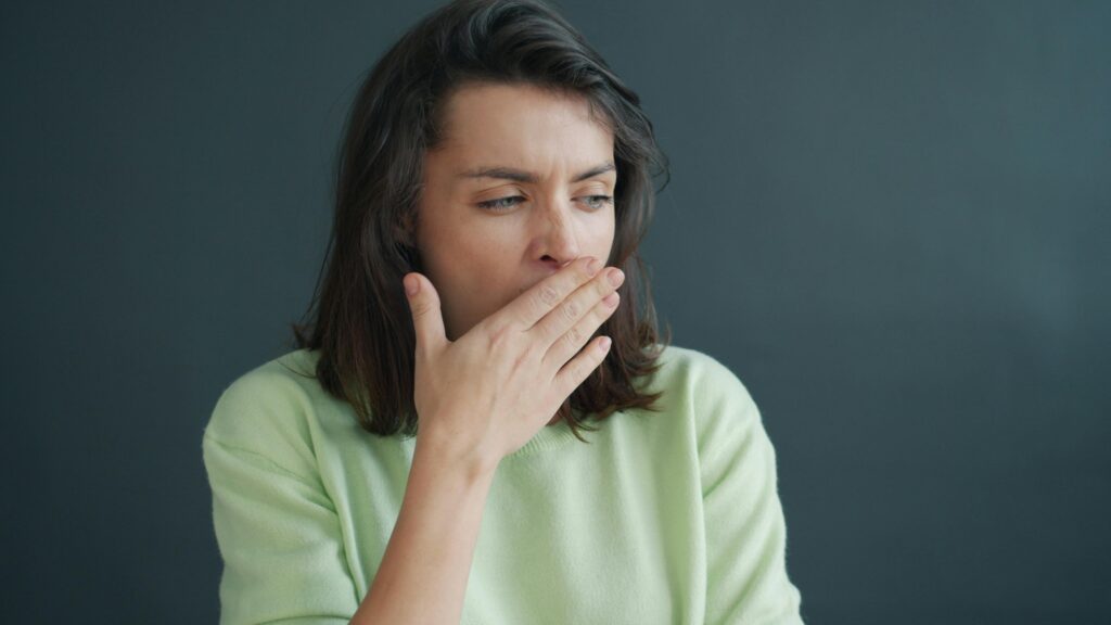 woman-yawning-with-hand-over-mouth-in-casual-setting
