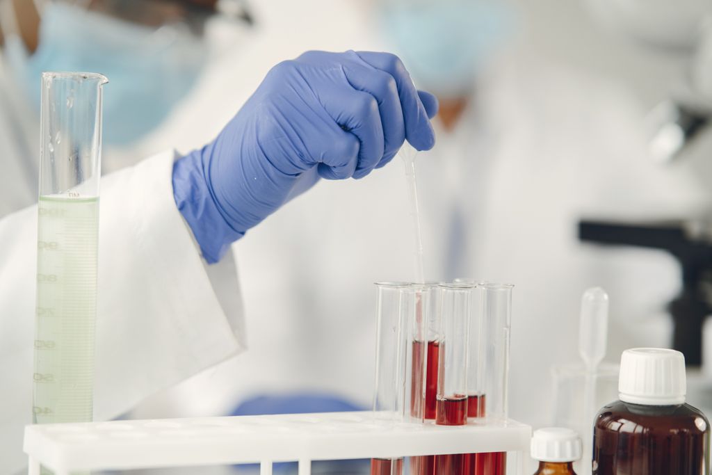 Scientist in protective gloves conducting research with test tubes in a lab setting.