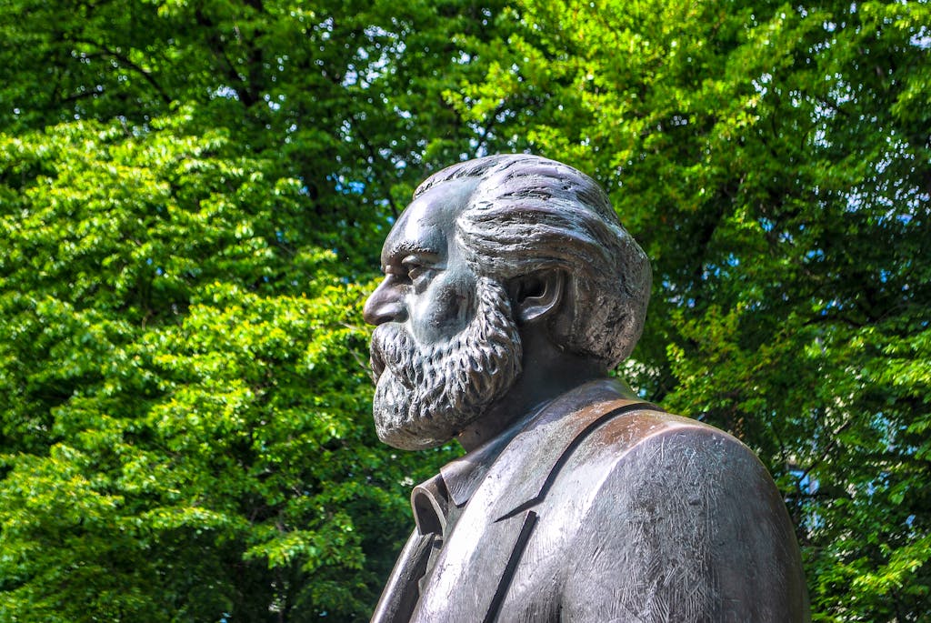 Side view of Karl Marx statue in a lush green Berlin park.