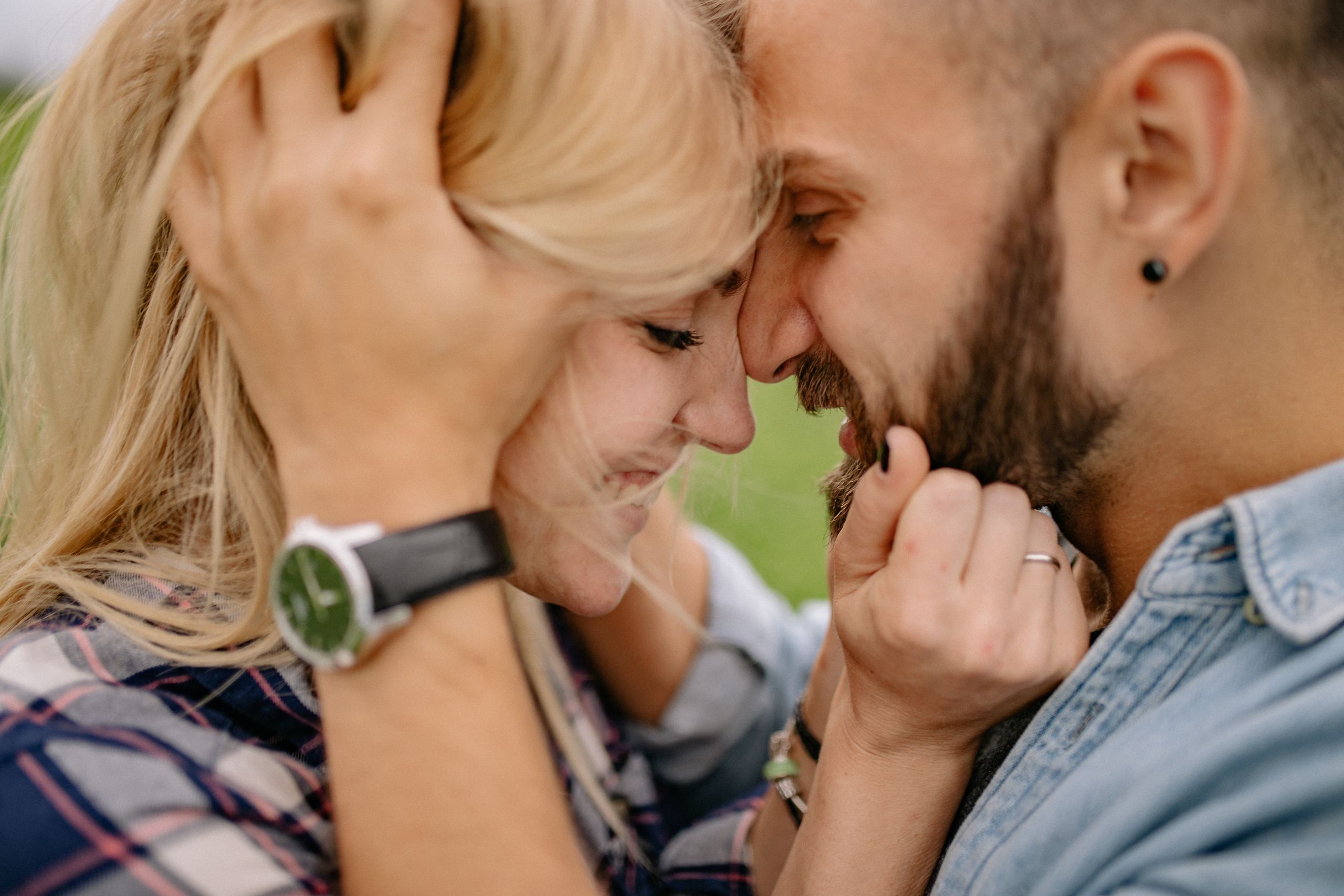 Smiling couple embraces warmly, expressing togetherness outdoors in natural setting.
