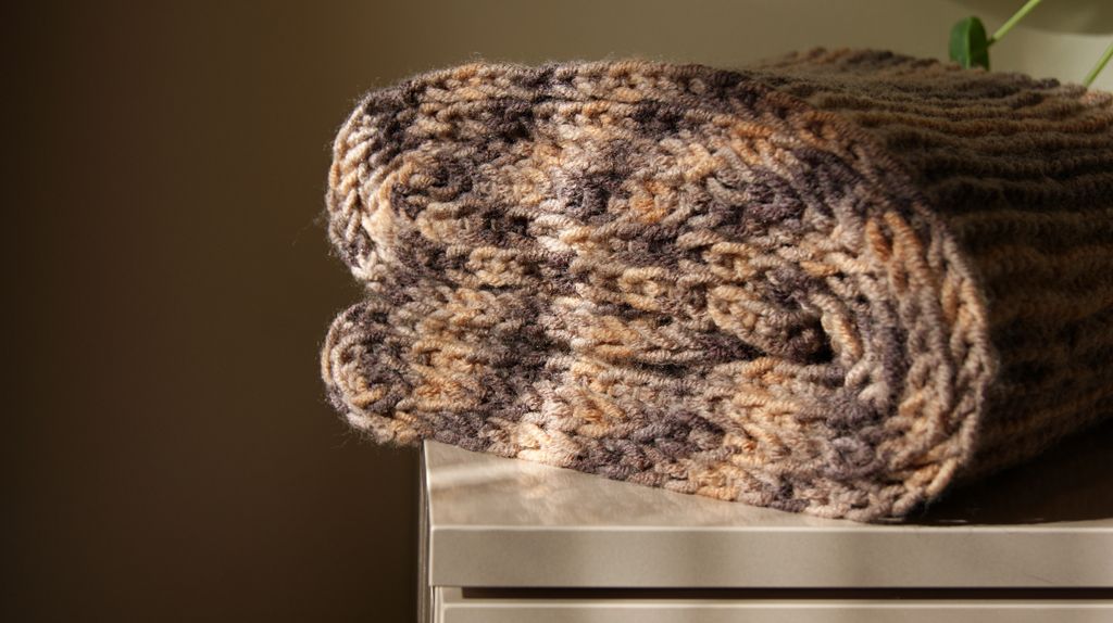 Soft knitted scarf with warm colors, folded neatly on a tabletop, illuminated by natural light.