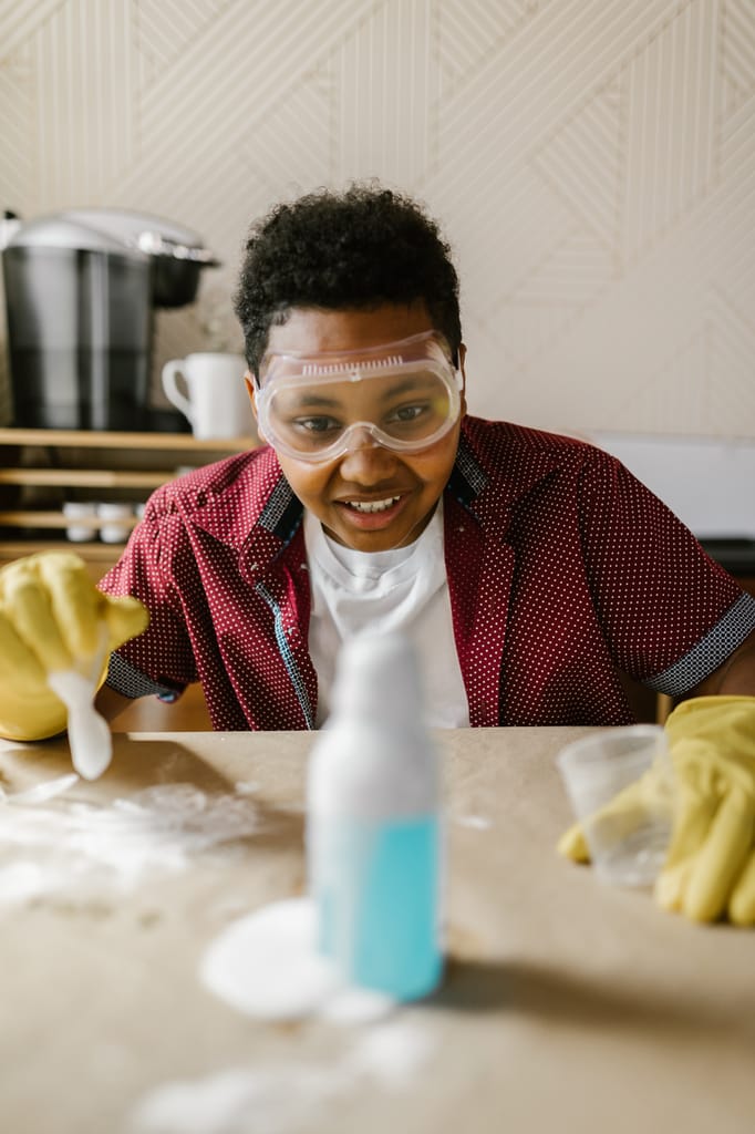 Teen engaged in hands-on chemistry experiment with safety gear at home.