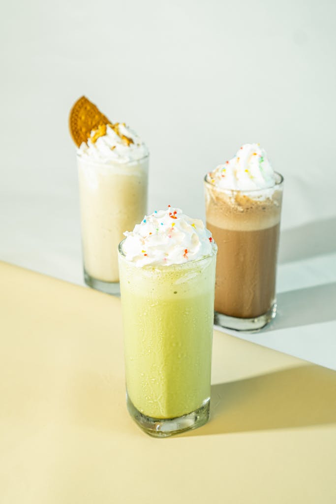 Three delicious milkshakes with whipped cream and toppings, perfect for a sweet treat.