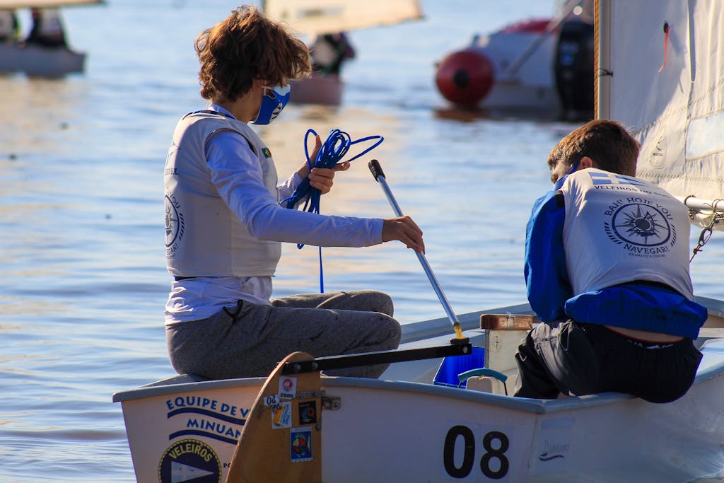 Two boys learning the art of sailing on a sunny day in calm waters.