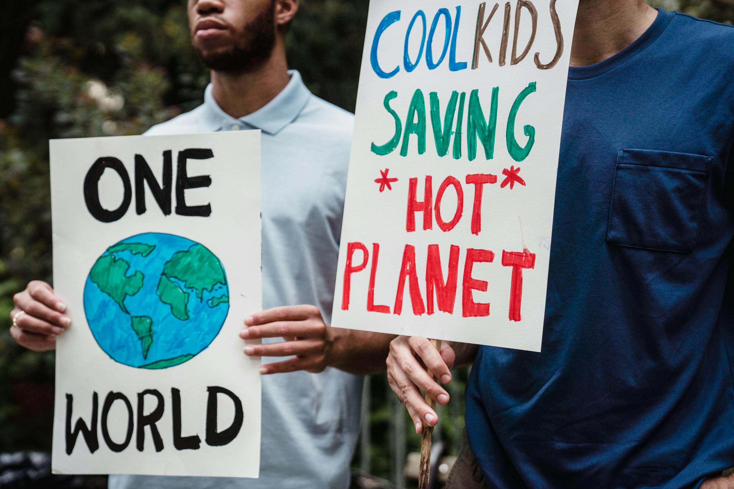 Two individuals hold signs advocating for environmental activism during a climate change protest.