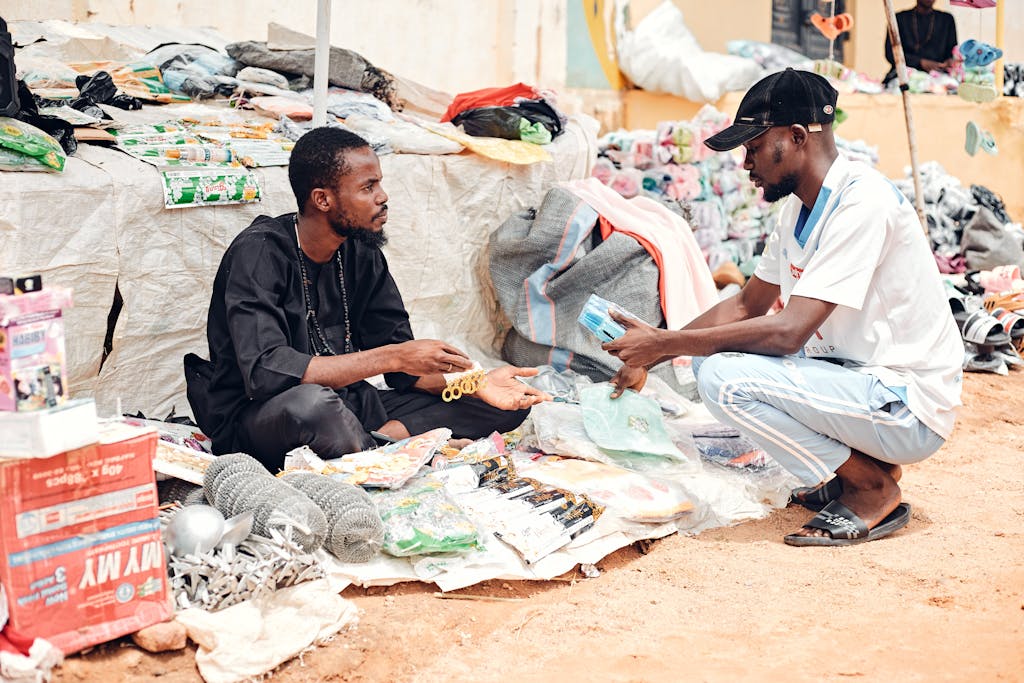Two men engaging in a transaction at an African outdoor market stall.